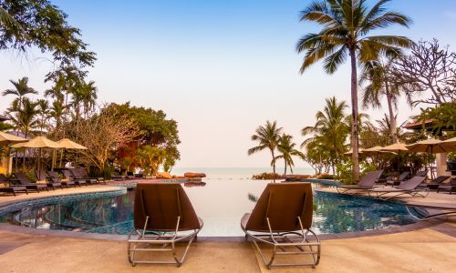 Beautiful luxury swimming pool with palm tree and sea background in hotel pool resort - Vintage Filter and Boost up color Processing